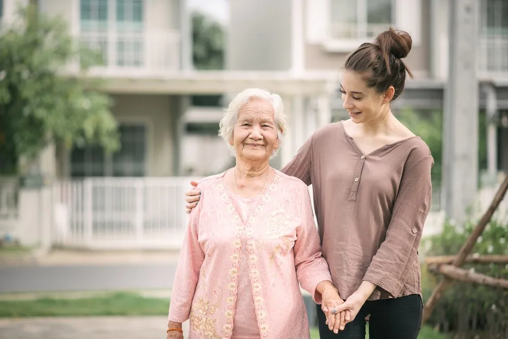 Caregiver walking outdoors with an older adult