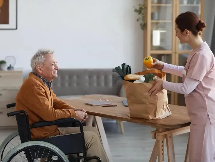 Caregiver bringing groceries to a senior at home