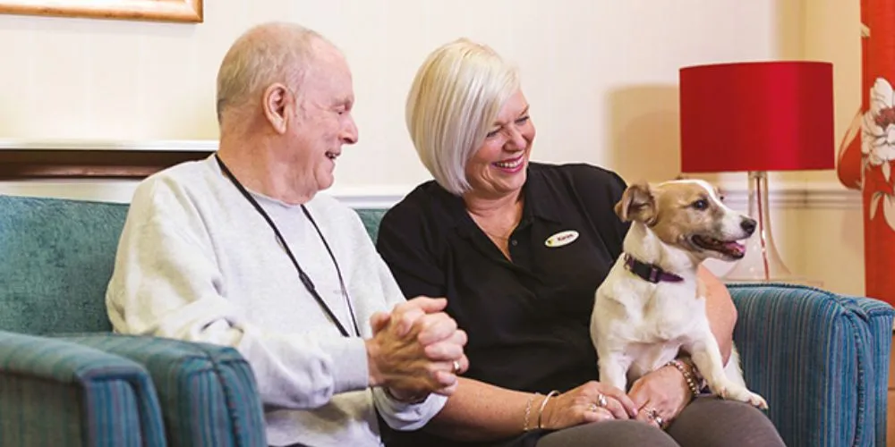 Caregiver and senior relaxing at home with a pet
